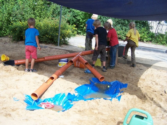 Kinder spielen mit Röhren und Wasser